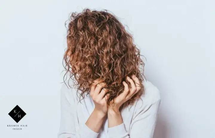 Frauen mit einer voluminösen Dauerwelle, die ihre Hände durch die Locken gleiten lassen.