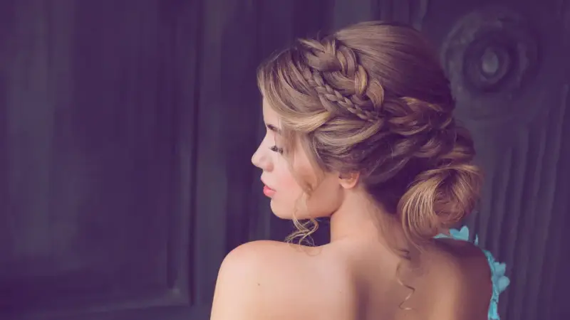 Elegante Frisur für Hochzeitsgäste: Ein kunstvoller Dutt mit geflochtenen Akzenten und zarten Locken.